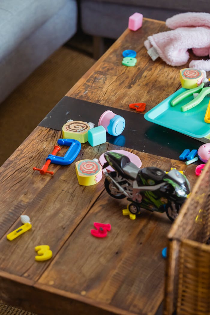 From above of toy mess on desk near gray sofa after children playing game